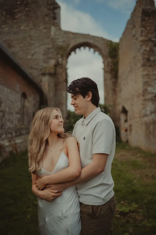 Boy holding his girlfriend from behind, and she's looking at him over her shoulder during their pre-wedding photoshoot