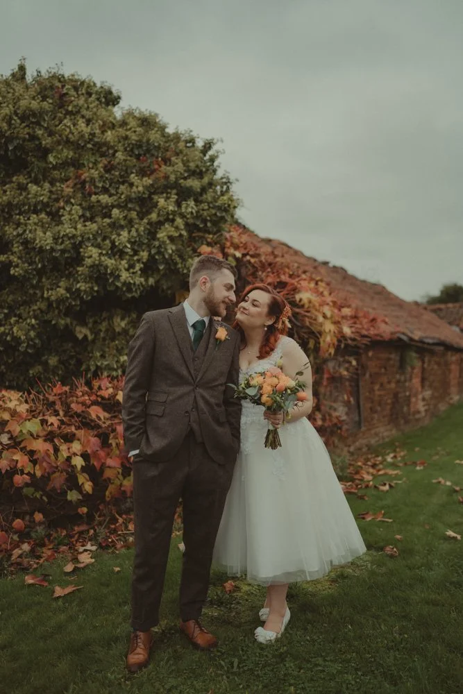 full body portrait of bride and groom smiling at each other at The Barns at Hunsbury Hill