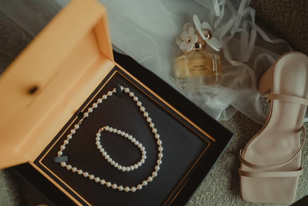 Details of necklace, perfume, shoes and veil