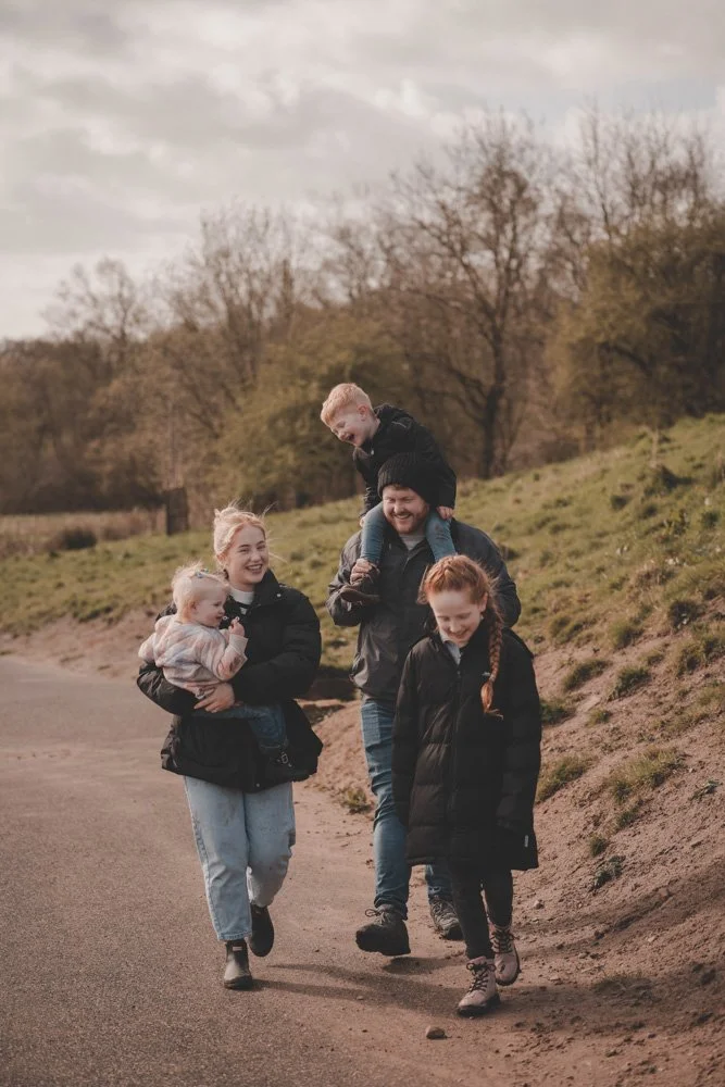 Mom, dad and their three kids walking up the road from Cuerden Valley Park