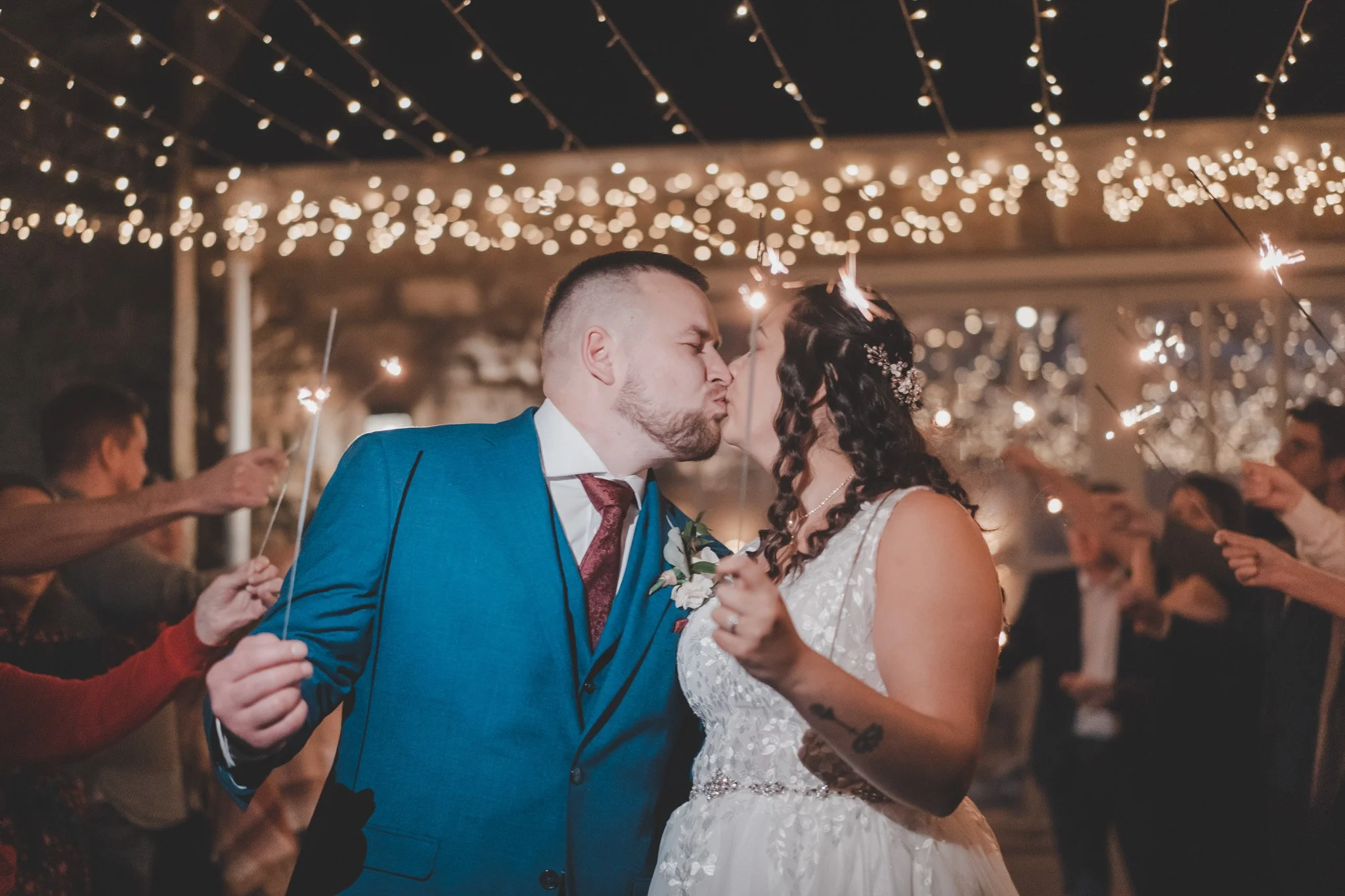 Bride and groom sharing a kiss holding sparkles in the middle of their guests at Cockliffe Country House, Nottingham