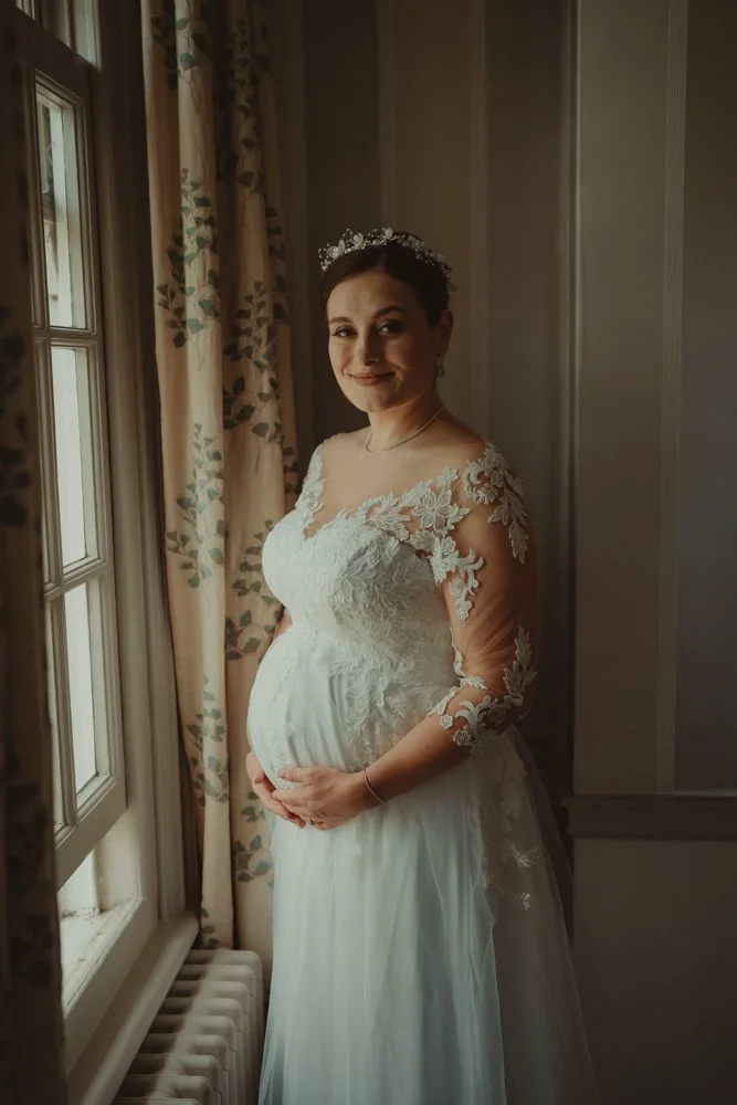 Portrait of a pregnant bride looking at the camera, on the morning of her wedding day, at Brockencote Hall Hotel, Kidderminster