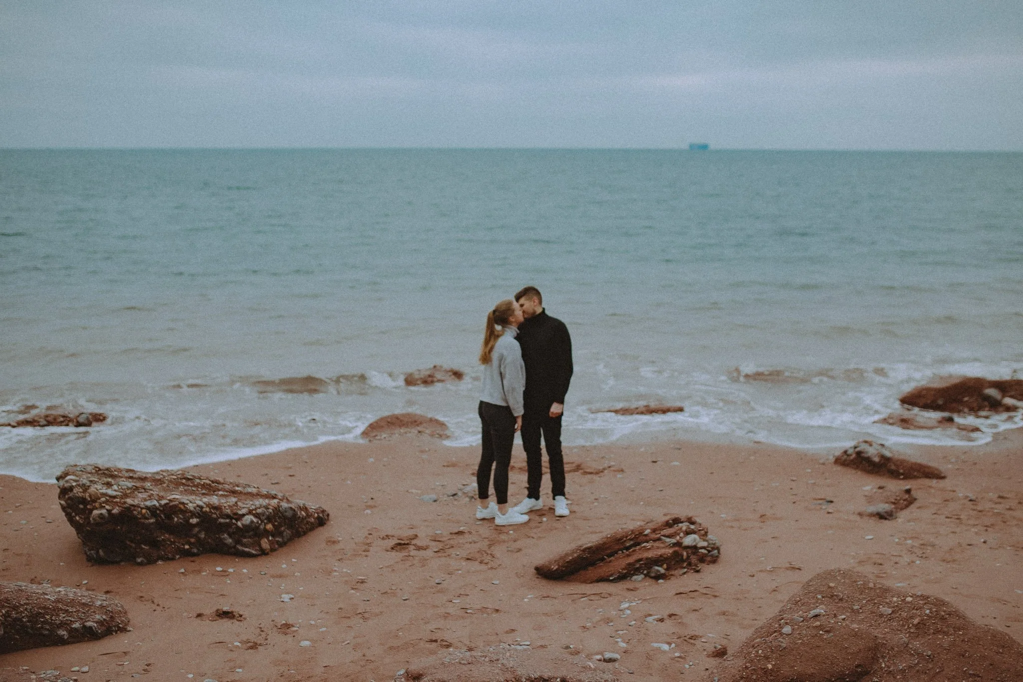 Couple sharing a kiss on Oddicombe beach, Cornwall