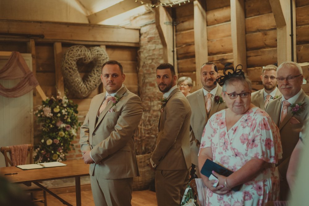 Groom waiting for the bride in front of the altar at the beginning of the wedding ceremony, at Wellington Barn, Wiltshire