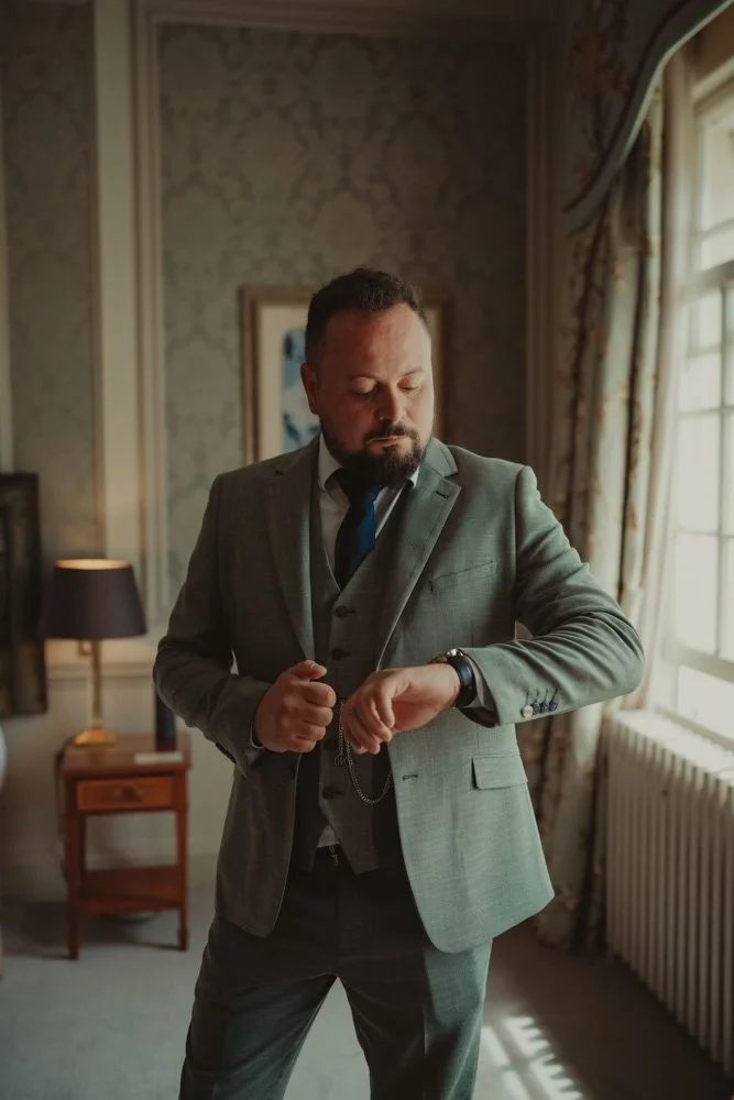 Groom checking the time right before his wedding ceremony in a room at Brockencote Hall Hotel, Kidderminster