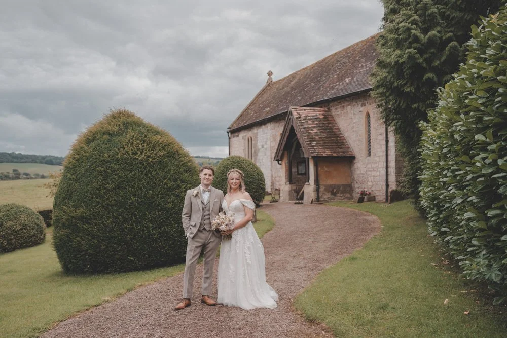Landscape photo of bride and groom looking at the camera at The Courtyard at Shelsley Walsh
