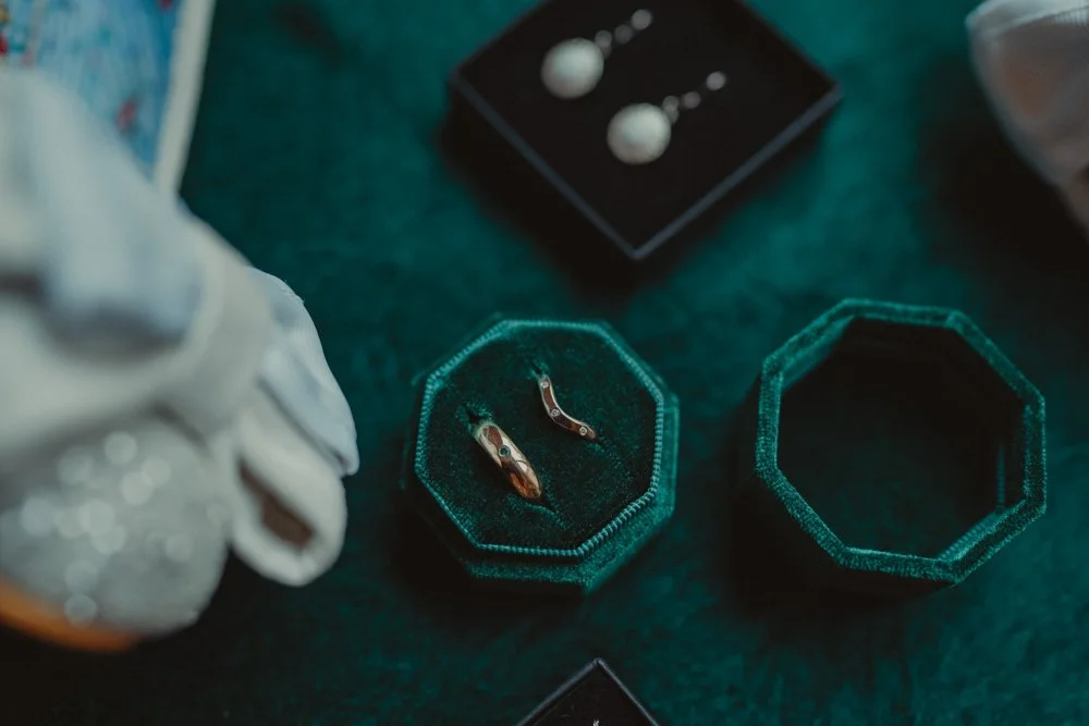 Details of wedding rings, ear rings, shoes, on a dark green background