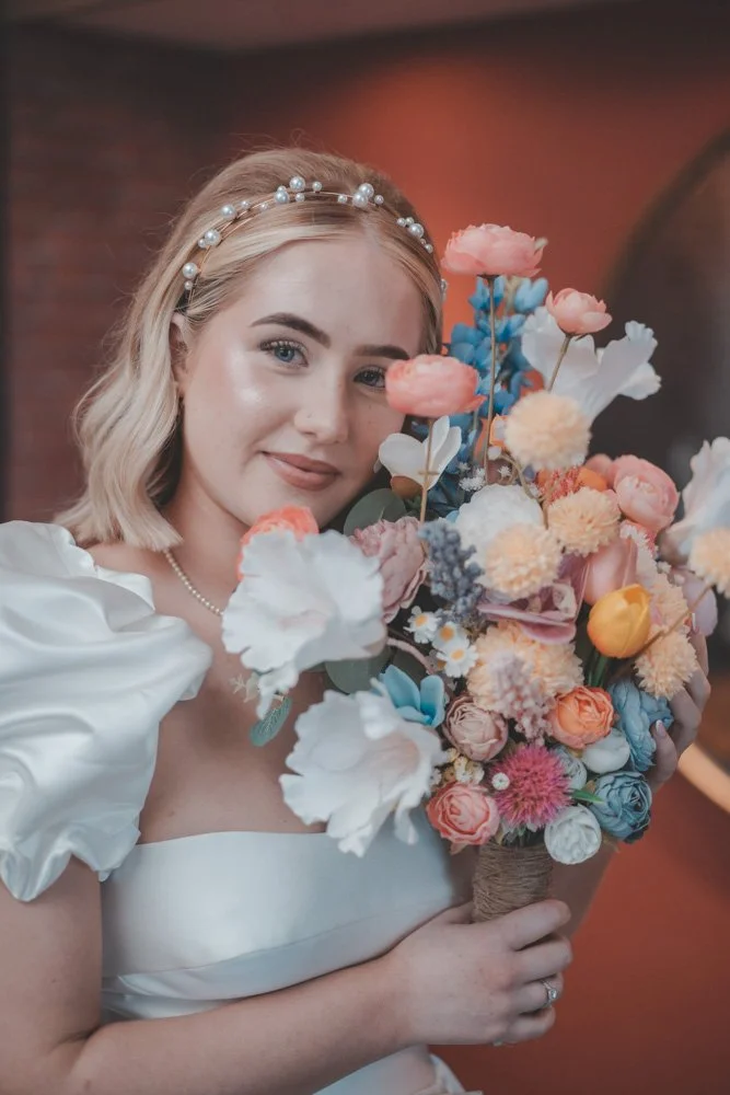 Portrait of a young bride holding her wedding flowers close to her face, at Whitehall Hotel Darwen