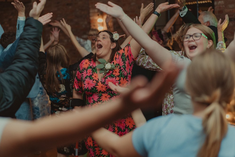 Wedding guests photographed with their hands in the air at a wedding at The Waterfront Barton Marina