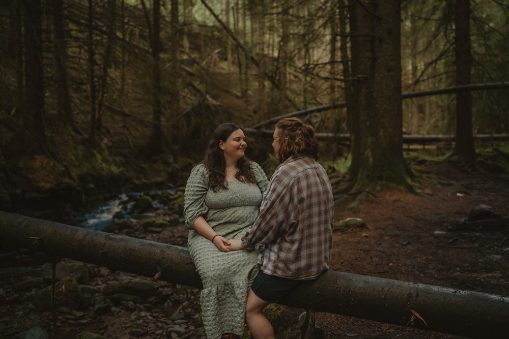 LGBTQ couple sitting on a tree branch, in the middle of Snake Woodland, UK