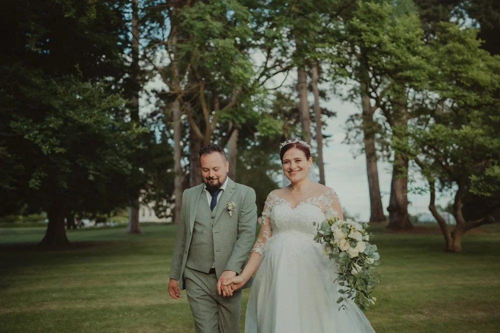 Bride and groom walking towards the camera and laughing on the grounds of Brockencote Hall Hotel, Kidderminster
