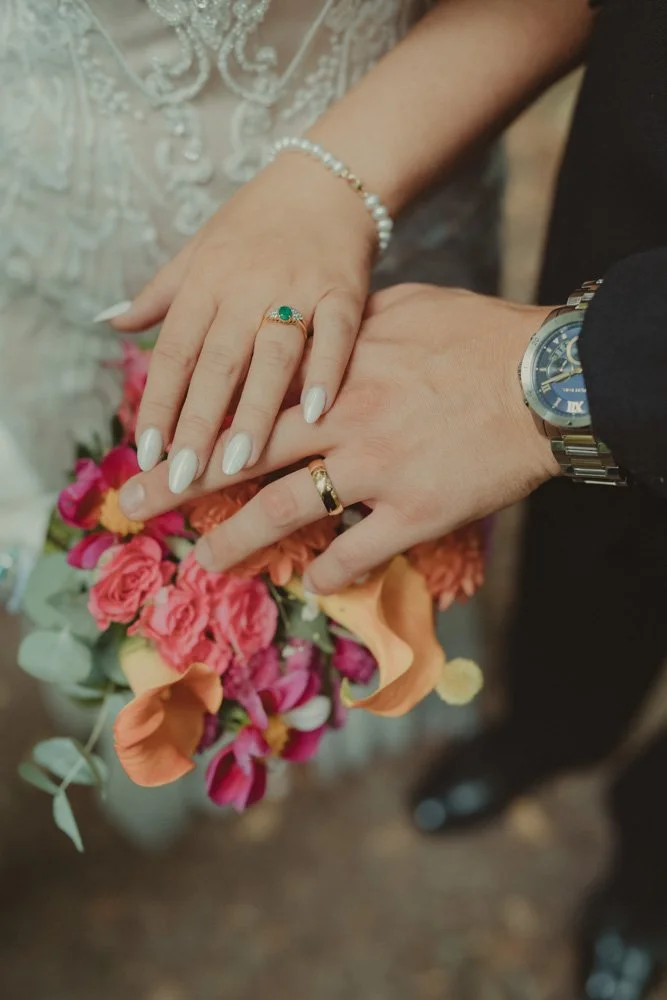 Detail of wedding rings on hands, and wedding flowers