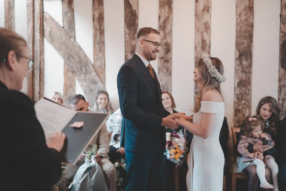 Bride and groom facing each other at their civil wedding ceremony, surrounded by guests, at Cheylesmore Manor House, Coventry