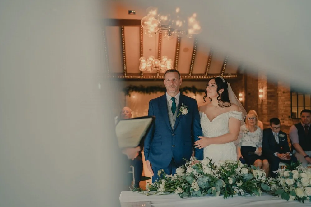 Bride and groom photographed in front of the altar during their wedding ceremony at The Waterfront Barton Marina