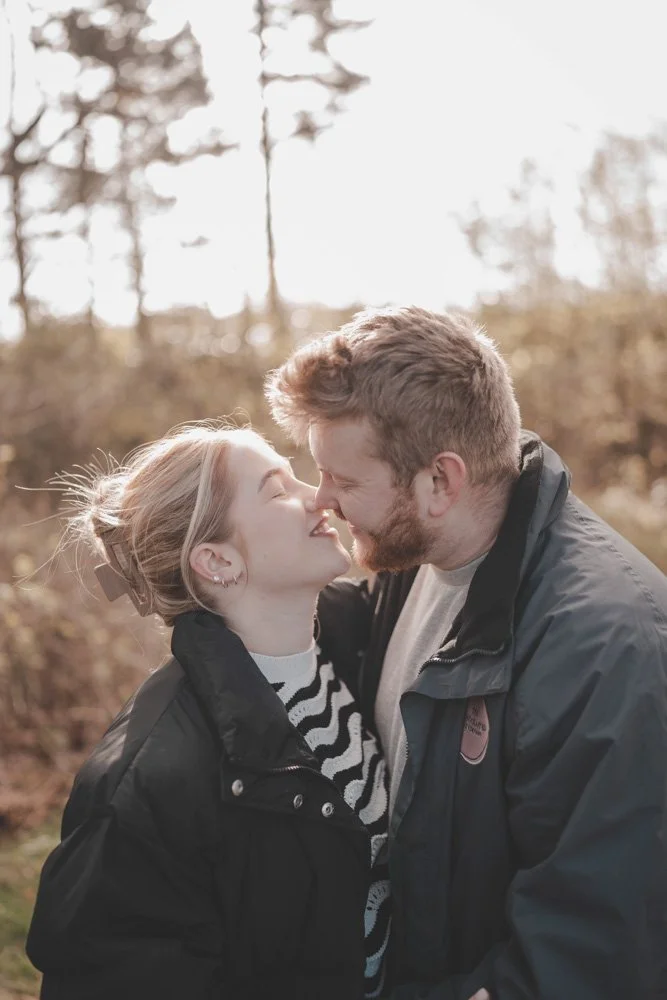 Portrait of couple kissing and smiling, in the middle of the woods at Cuerden Valley Park