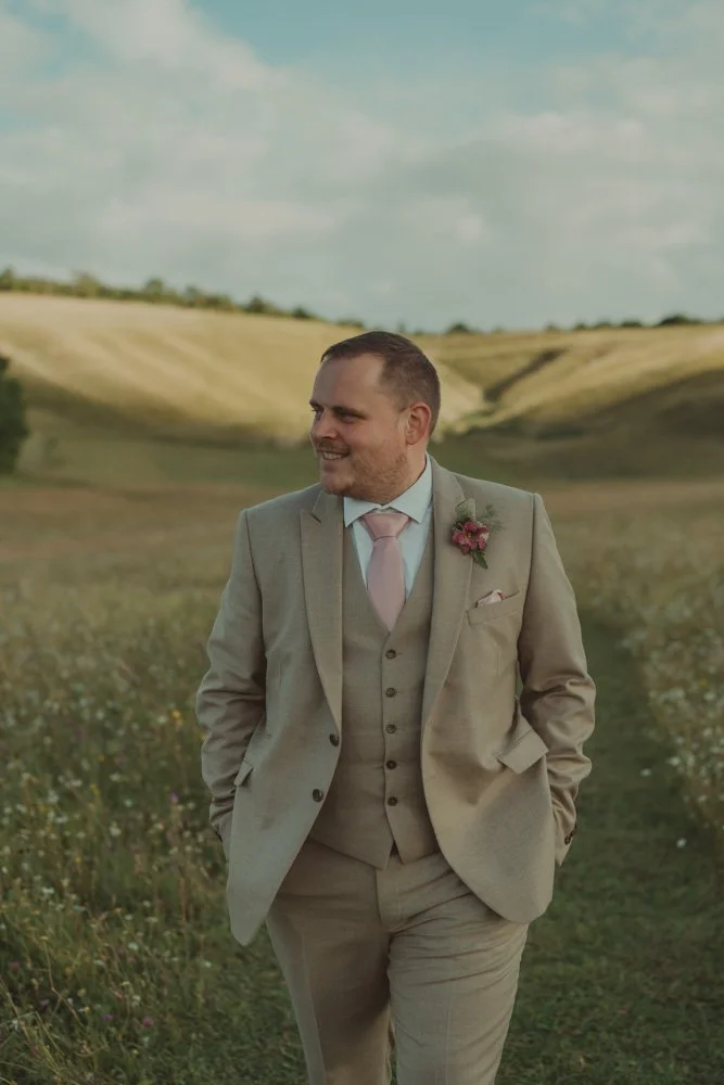 Groom walking towards the camera, hand in the pockets, looking away at Wellington Barn, Wiltshire