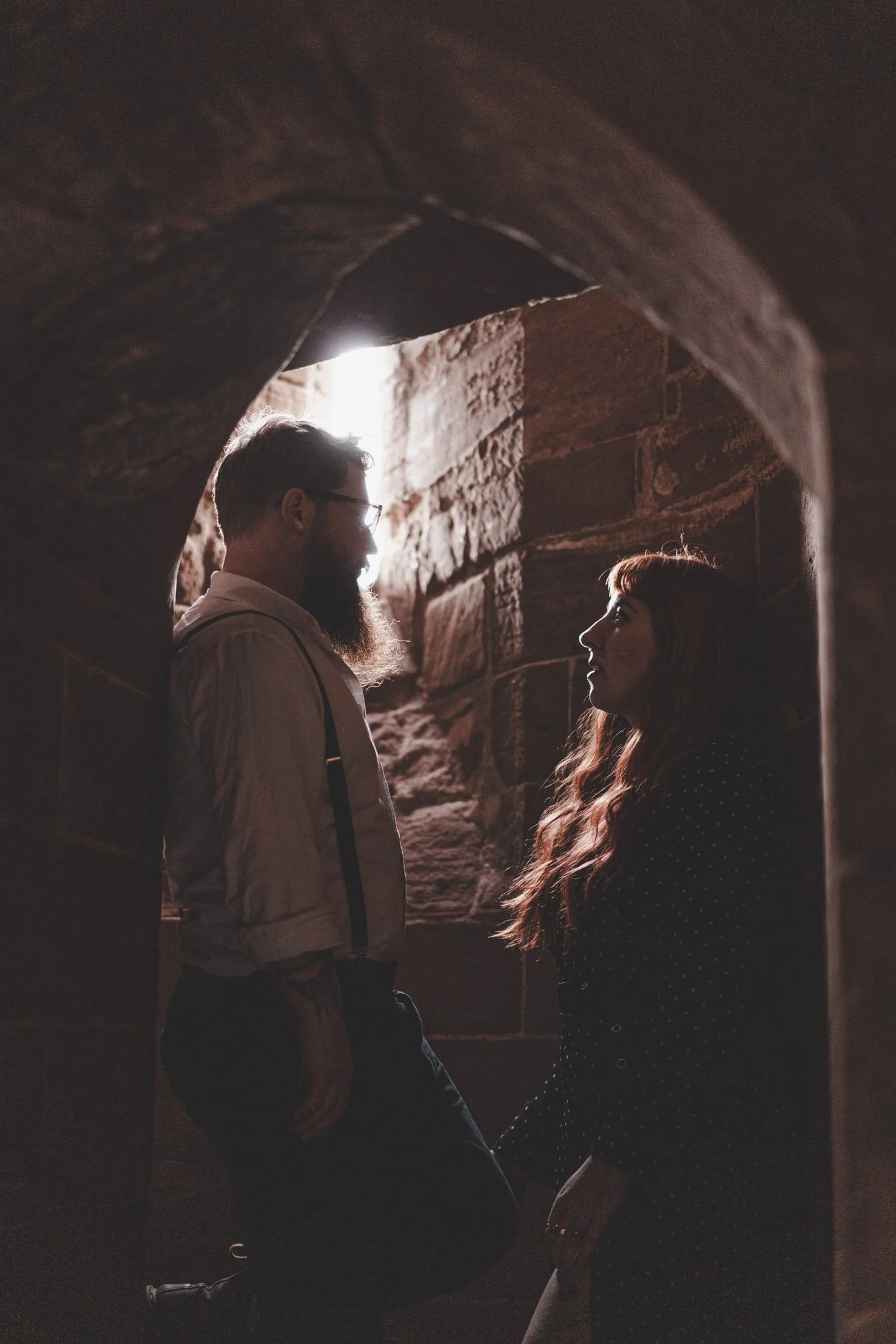Couple looking at each other in dim light inside of Kenilworth Castle 