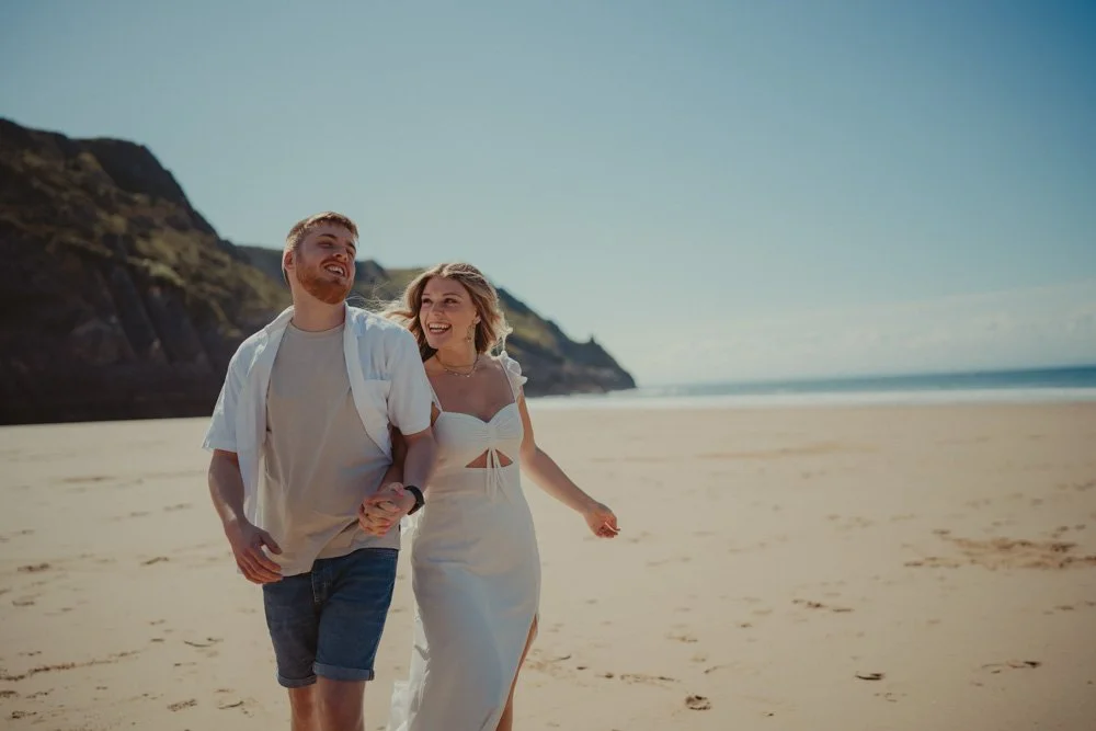 Young couple photographed on a sunny day, at a pre-wedding photo session at Three Cliffs Bay, Wales