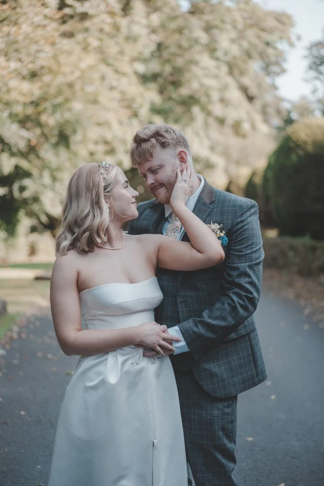 Portrait of groom and bride holding each other on the grounds of Whitehall Hotel Darwen