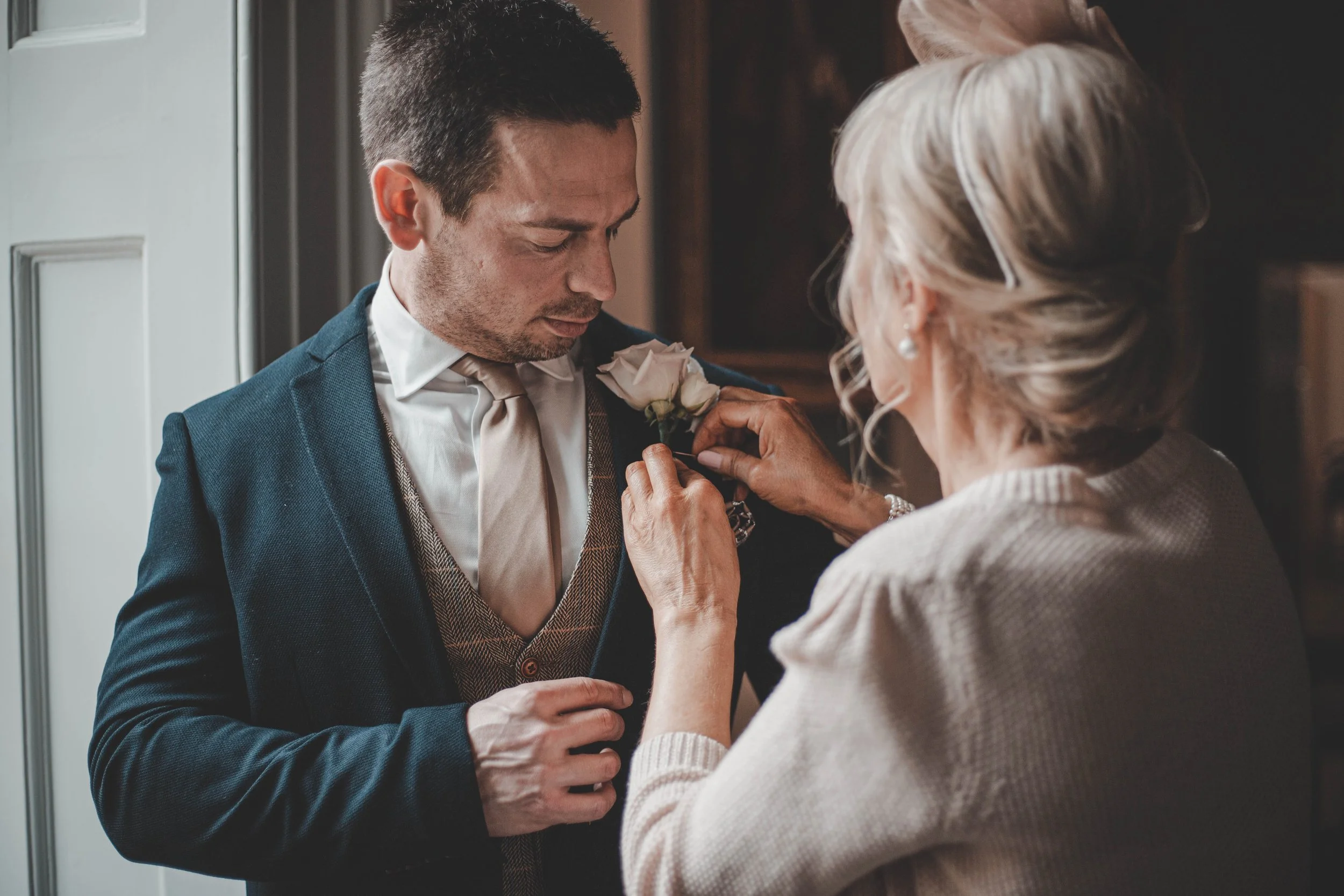 Mother of the groom helping him with his boutonnière