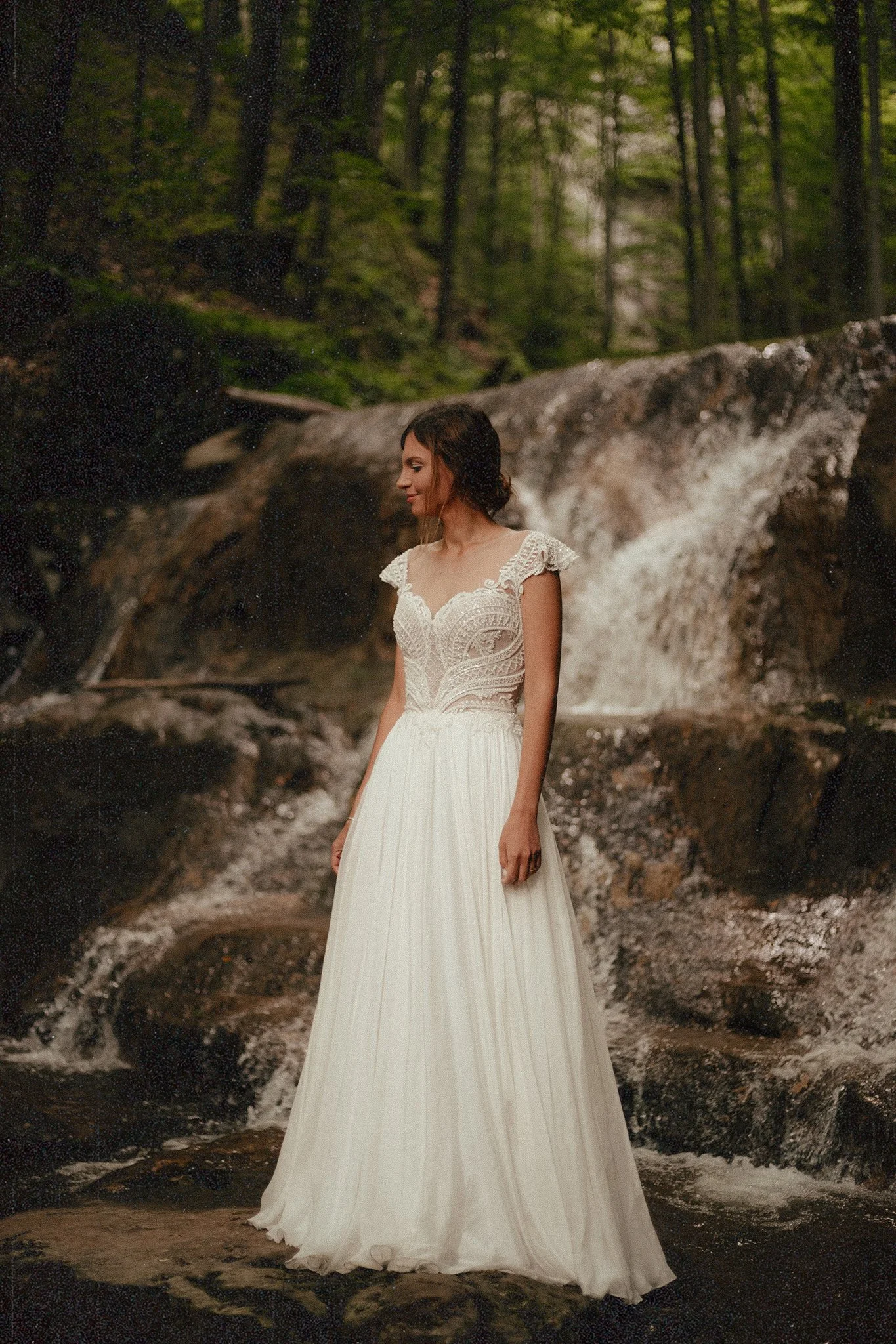 Bride photographer near a waterfall in the middle of the woods