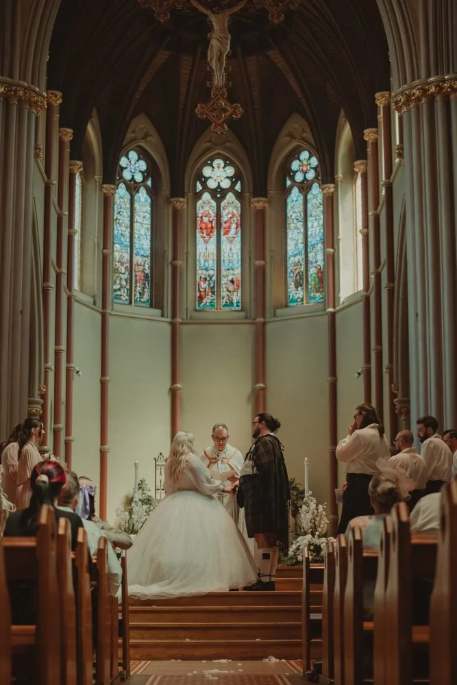 Bride and groom in front of the altar at a religious ceremony at St. John's Portsmouth Catholic Cathedral