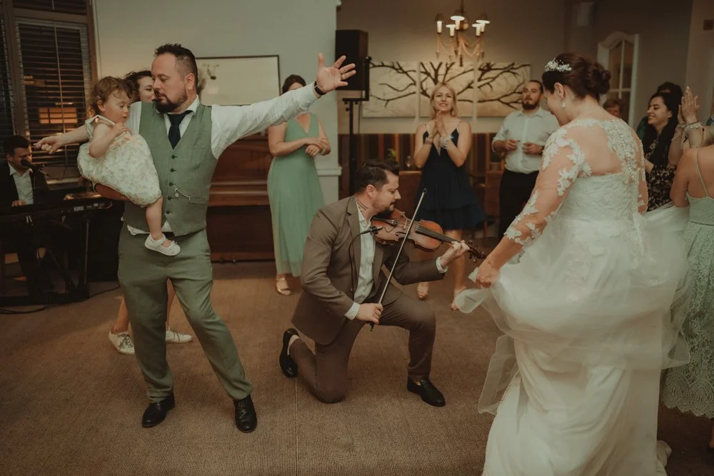 Alex Man playing the violin on the dance floor at Brockencote Hall Hotel, Kidderminster, surrounded by wedding guests and bride and groom 