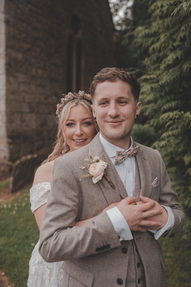 Close-up portrait of bride holding her husband from behind, on their wedding day at The Courtyard at Shelsley Walsh