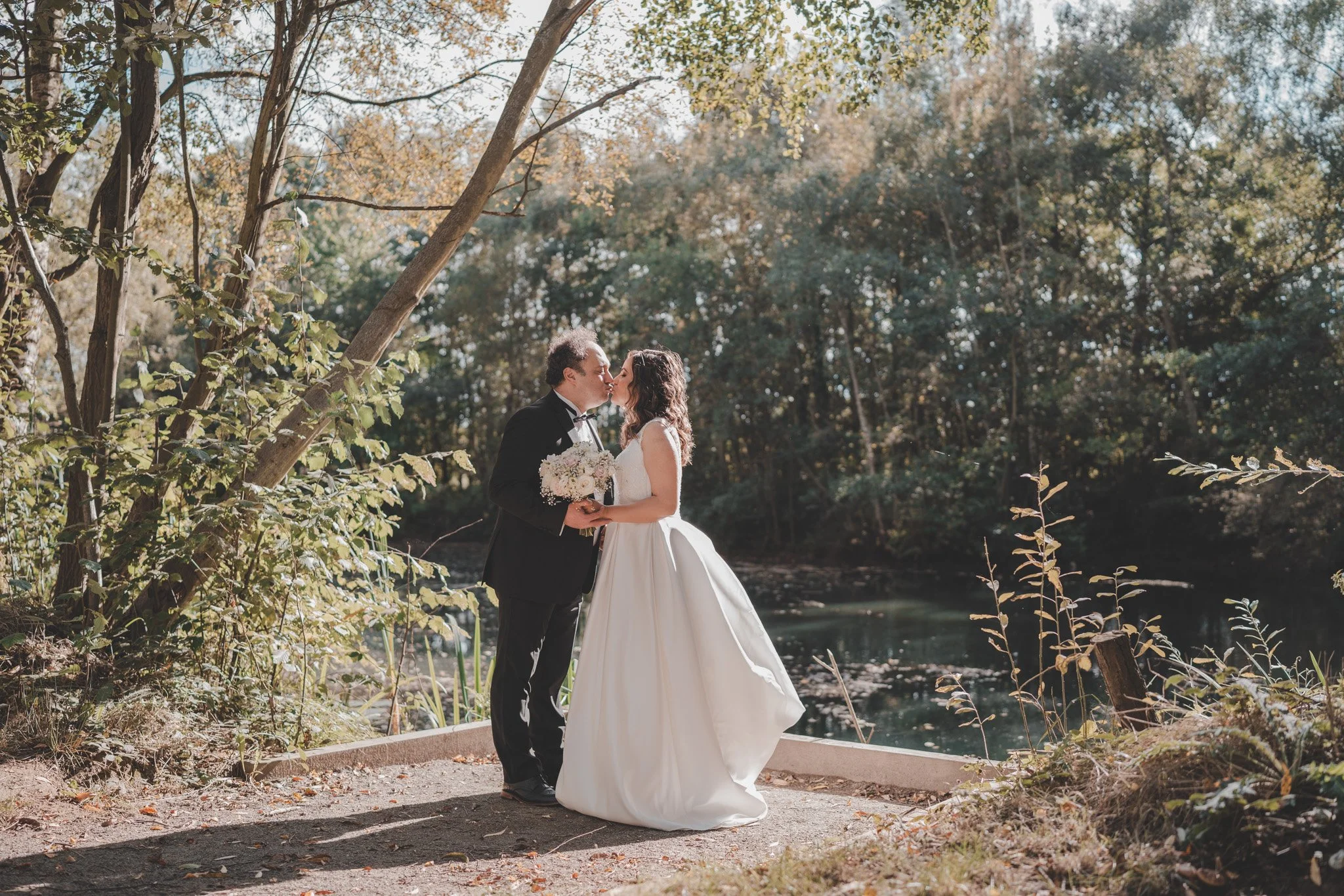 Bride and groom kissing on a sunny day at Delapre Lake, Northampton