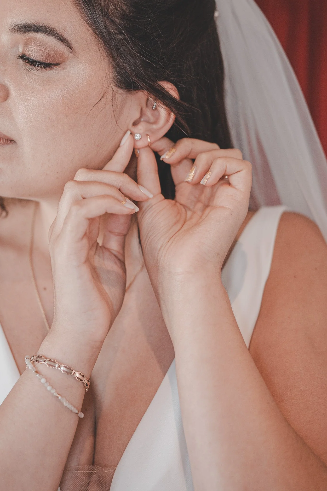 Bride putting on her ear rings during bride prep on the morning of her wedding day 