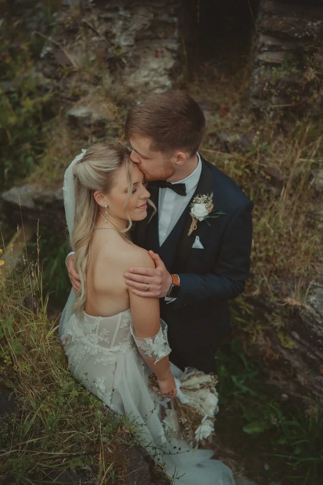 Groom kissing his wife's forehand during the couple photoshoot on their wedding day, in Wales