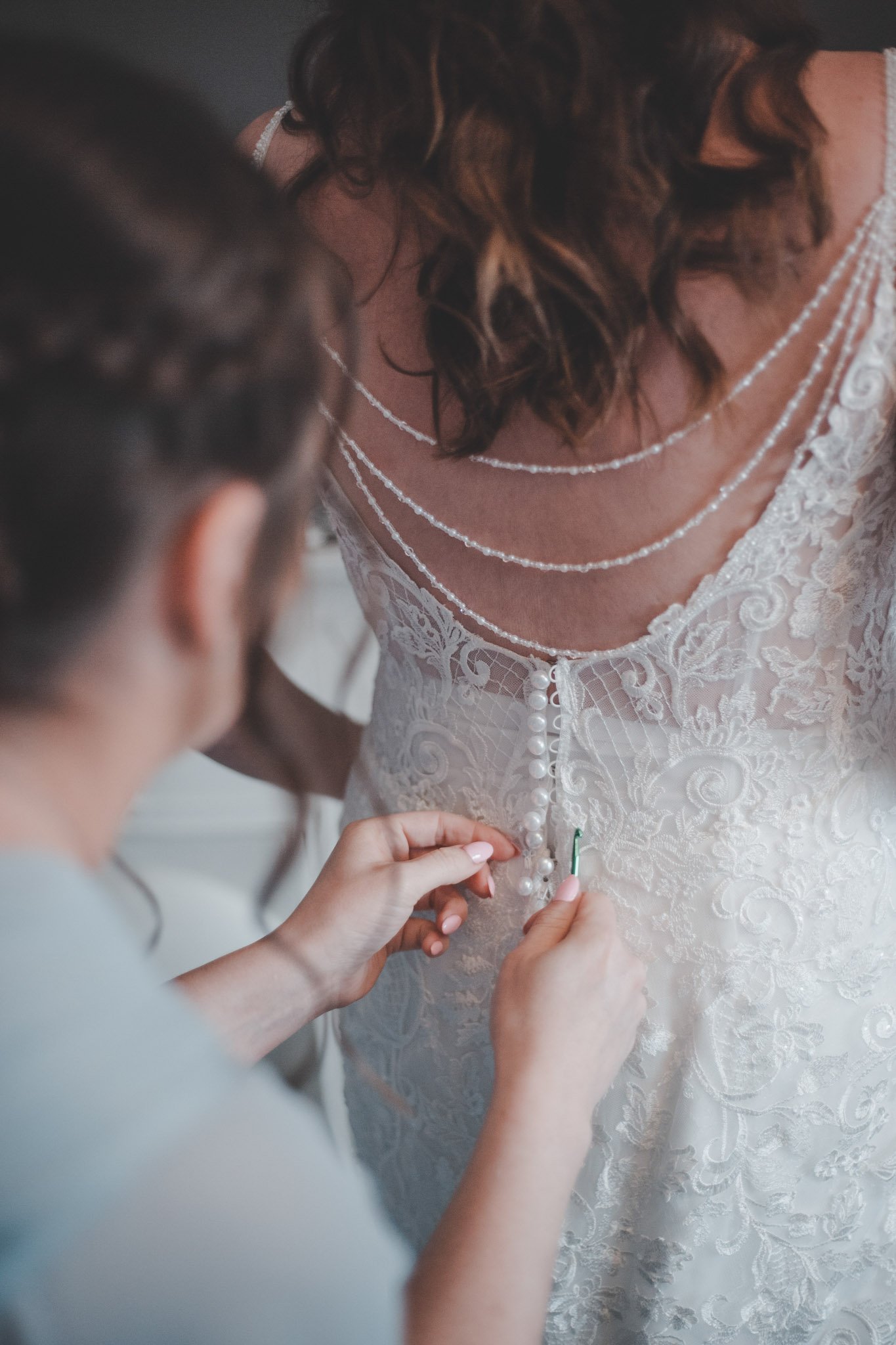 Bridesmaid helping bride dress up