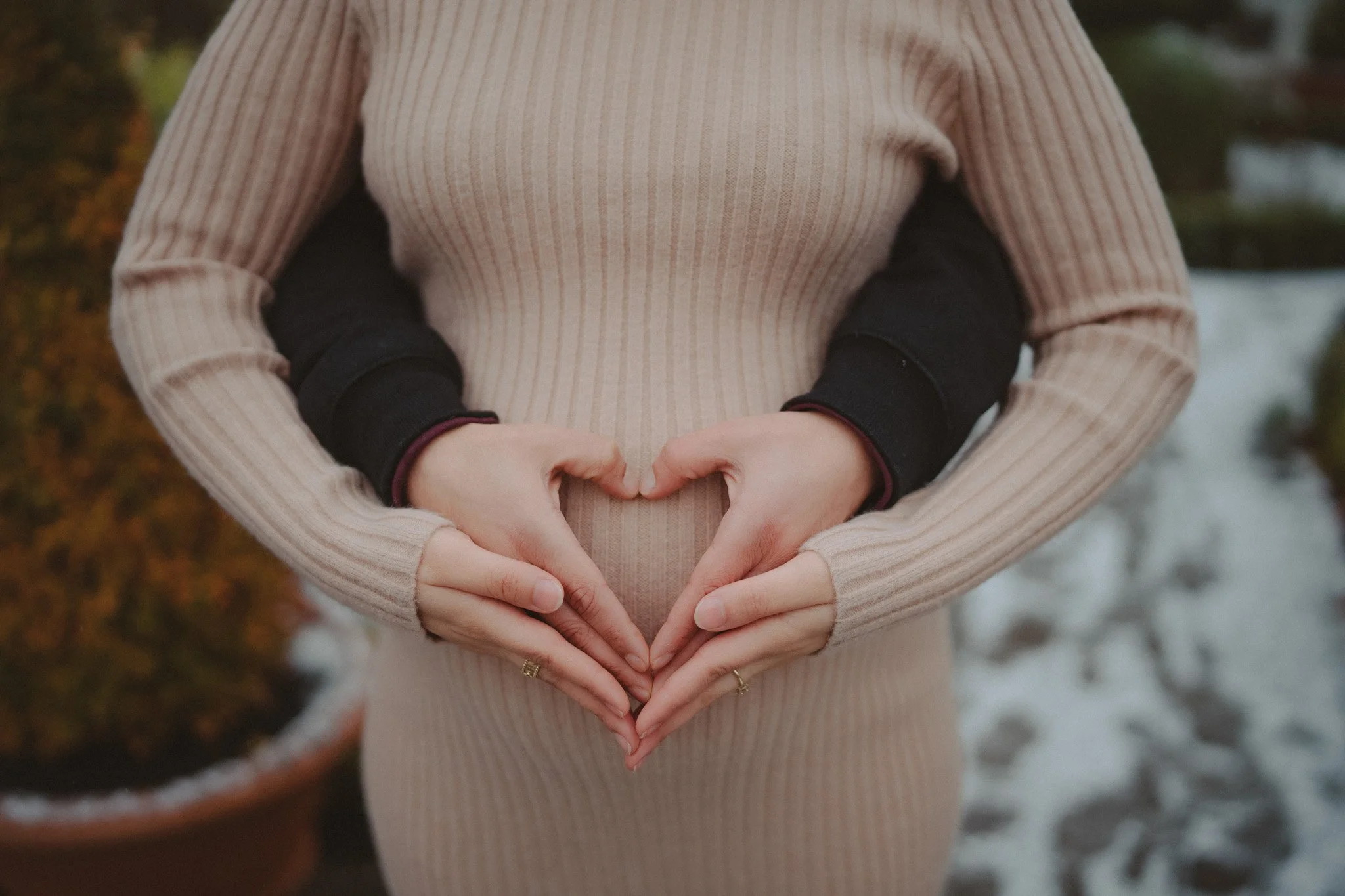 Details of hands forming a heart over a pregnant women's belly