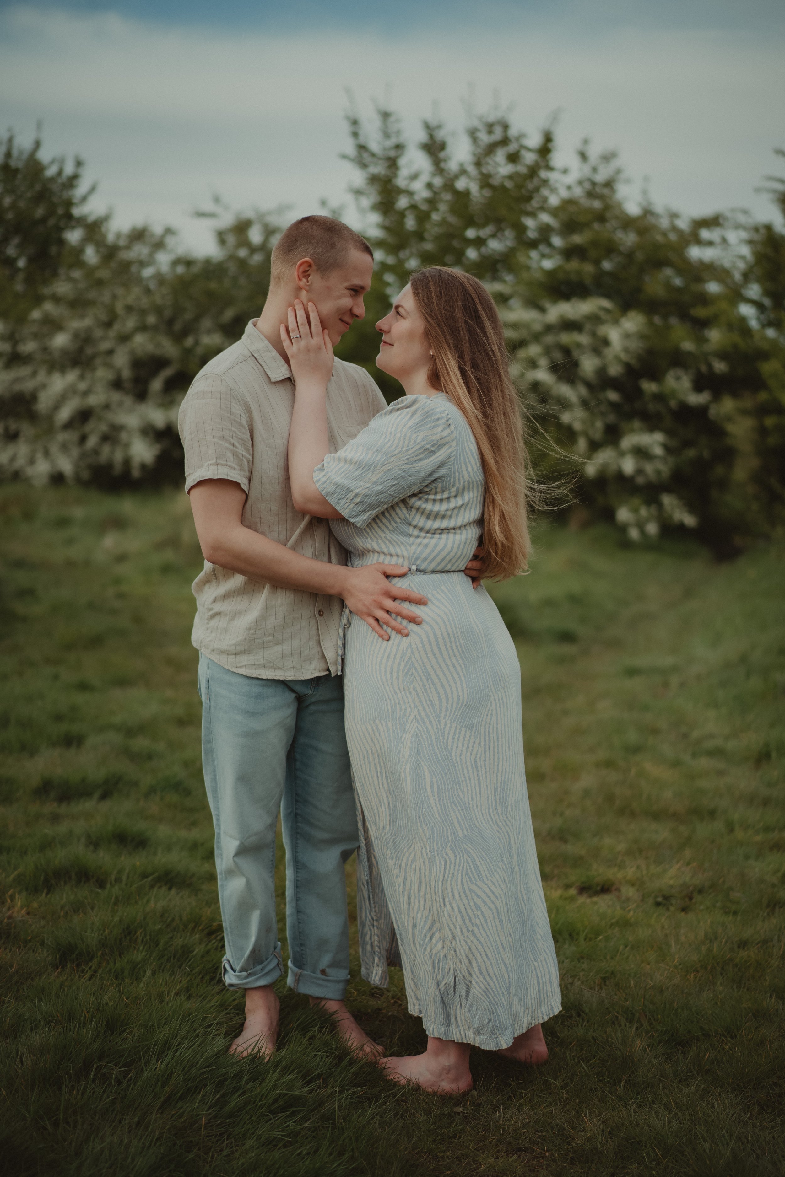 Barefoot couple holding each other on a field in Hoveringham., at their save the date photoshoot
