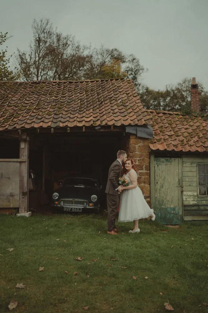 Vertical photo of groom kissing his wife's forehead at their wedding in the Midlands, UK