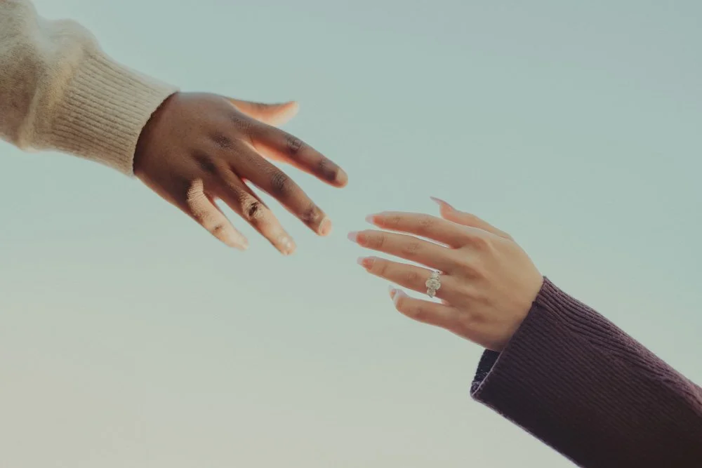 Close-up photo of hands reaching out for each other, with details of engagement ring, in London