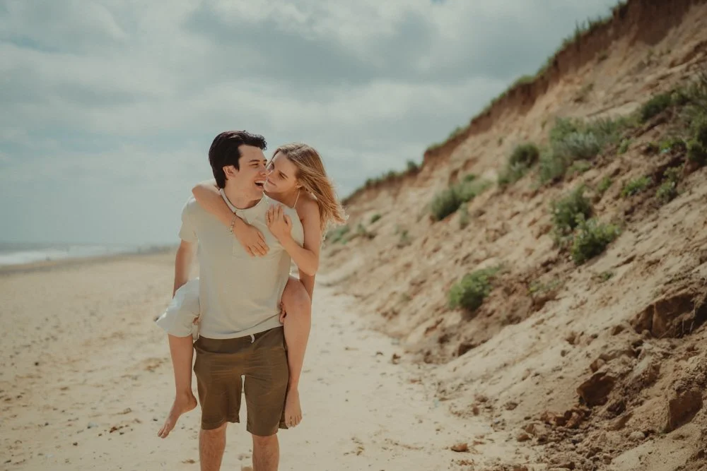 Man carrying his girlfriend on his back on  Covehithe Beach