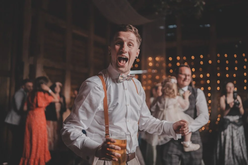 Groom having a great time on the dance floor, with a drink in his hand, at The Courtyard at Shelsley Walsh