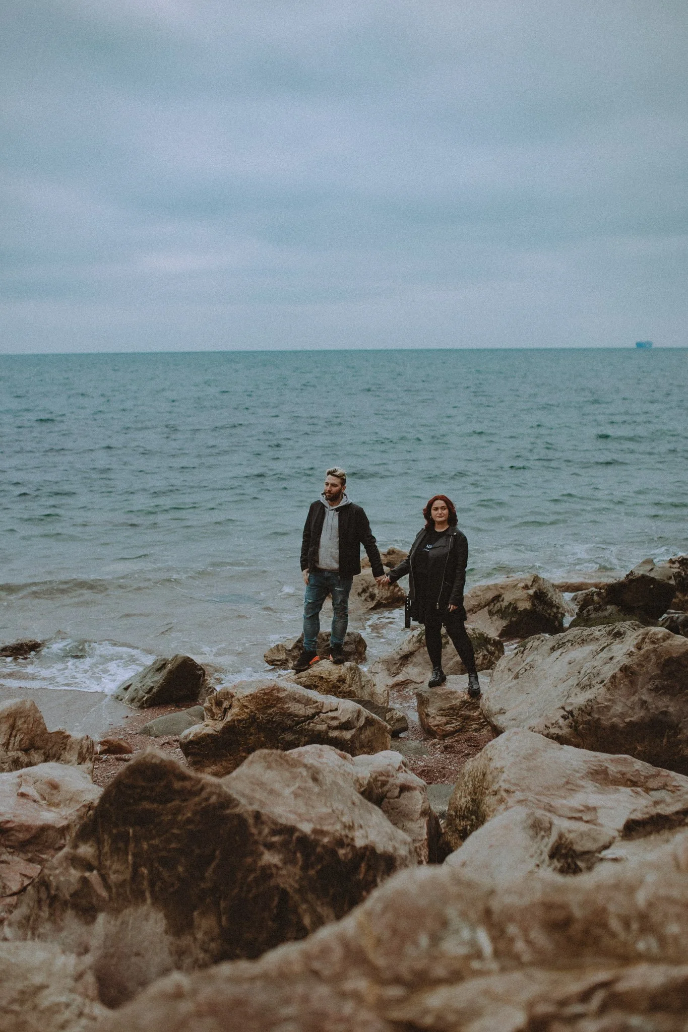 Couple holding hands in front of the sea, in Cornwall