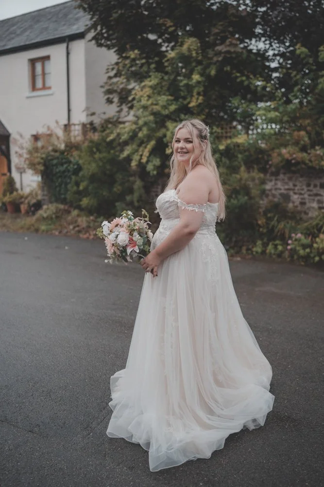 Full body photo of a bride holding her flowers on her wedding day, Wales, UK