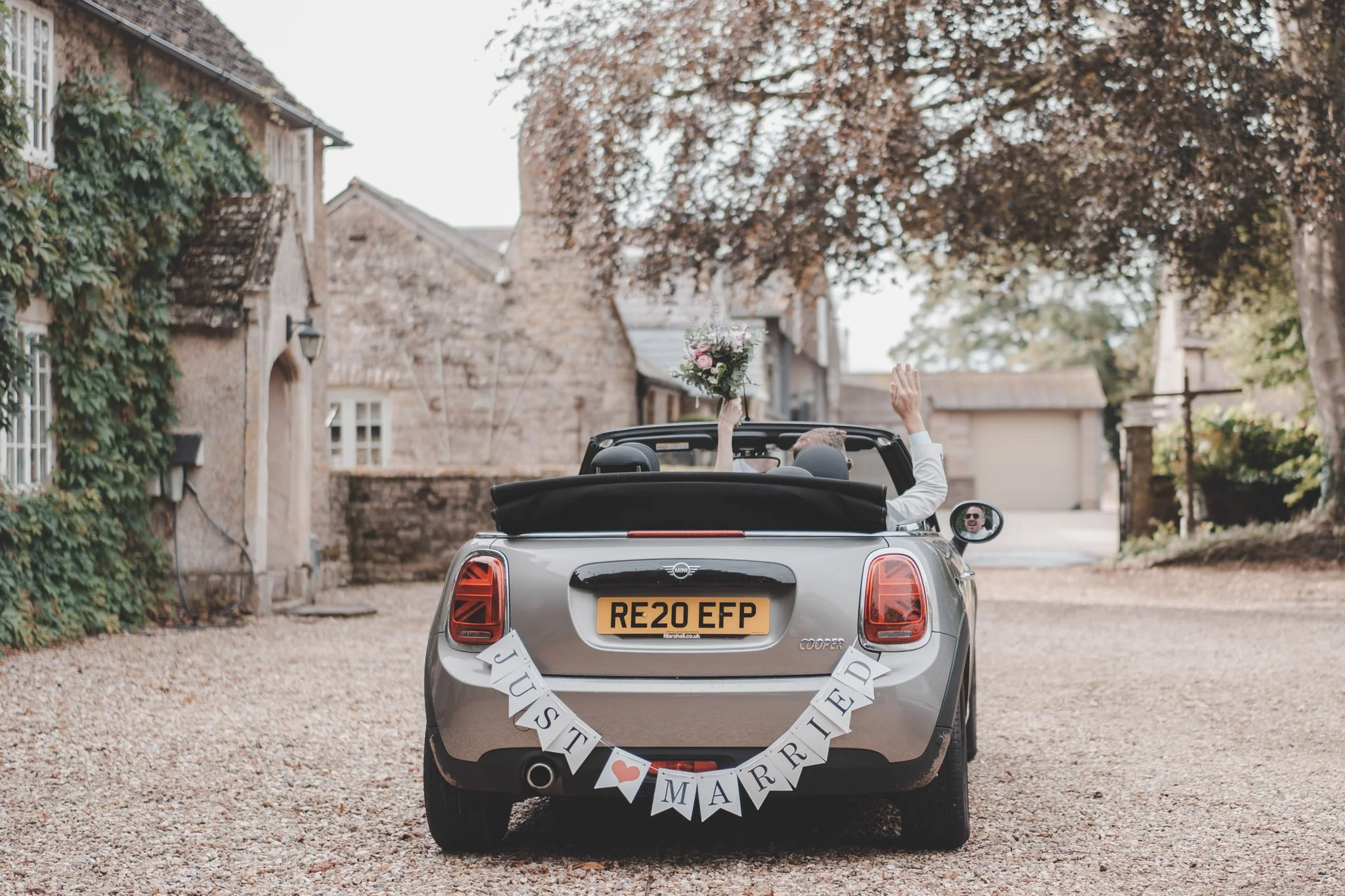 Bride and groom leaving Friars Court, Clanfield, Oxfordshire in a wedding decorated car