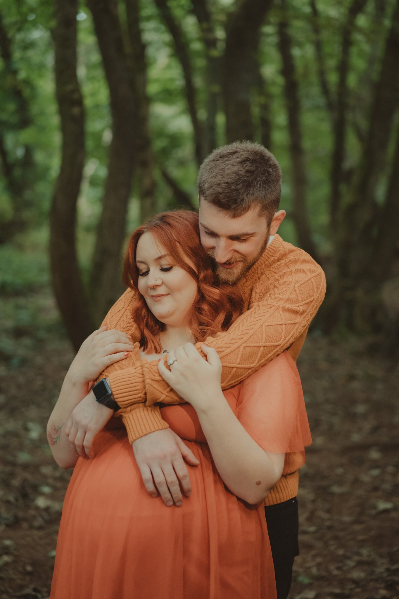 Man holding his pregnant future bride in his arms in Derbyshire forest park