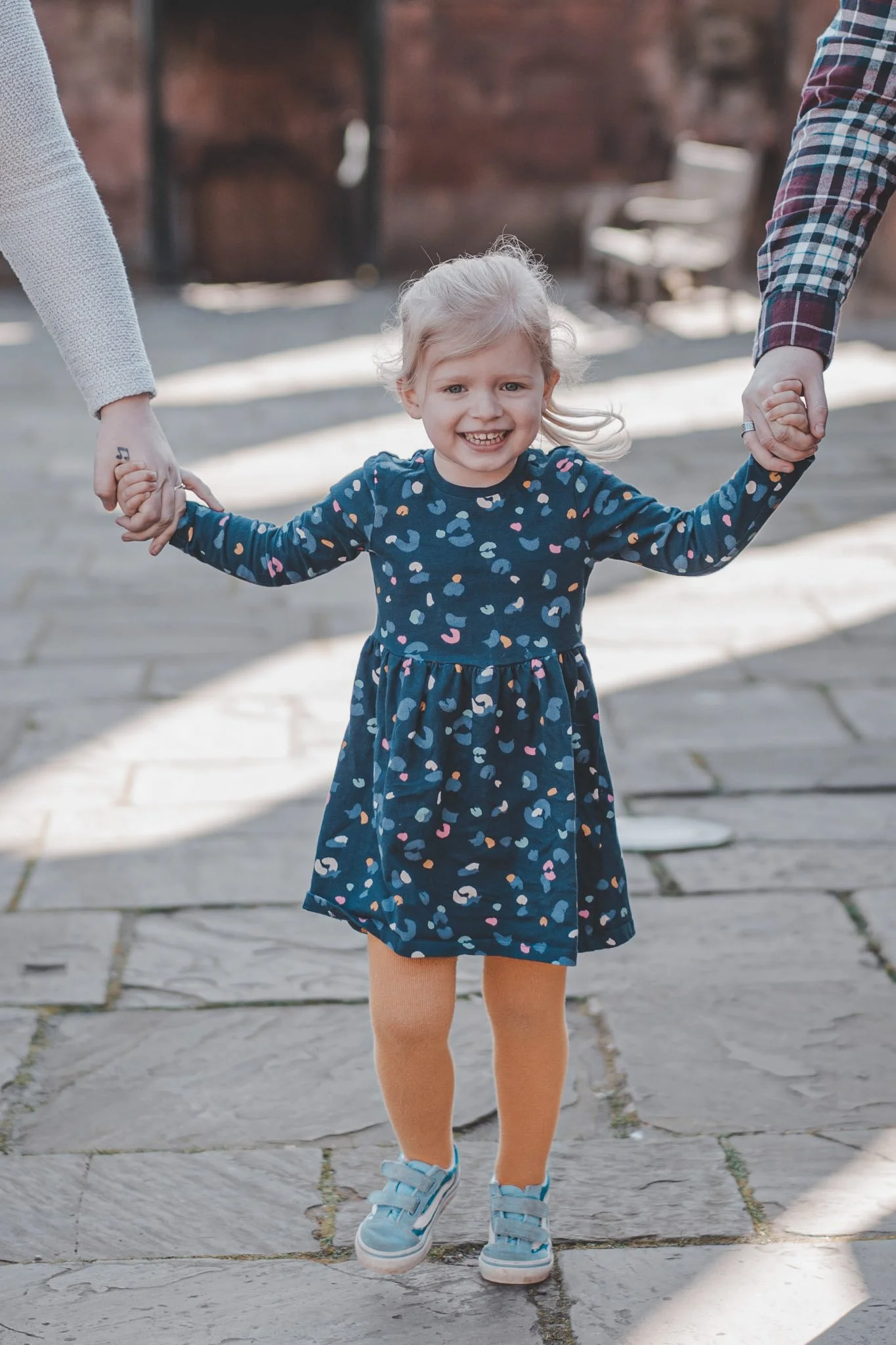 LGBT married couple holding their daughters hand at a family shooting