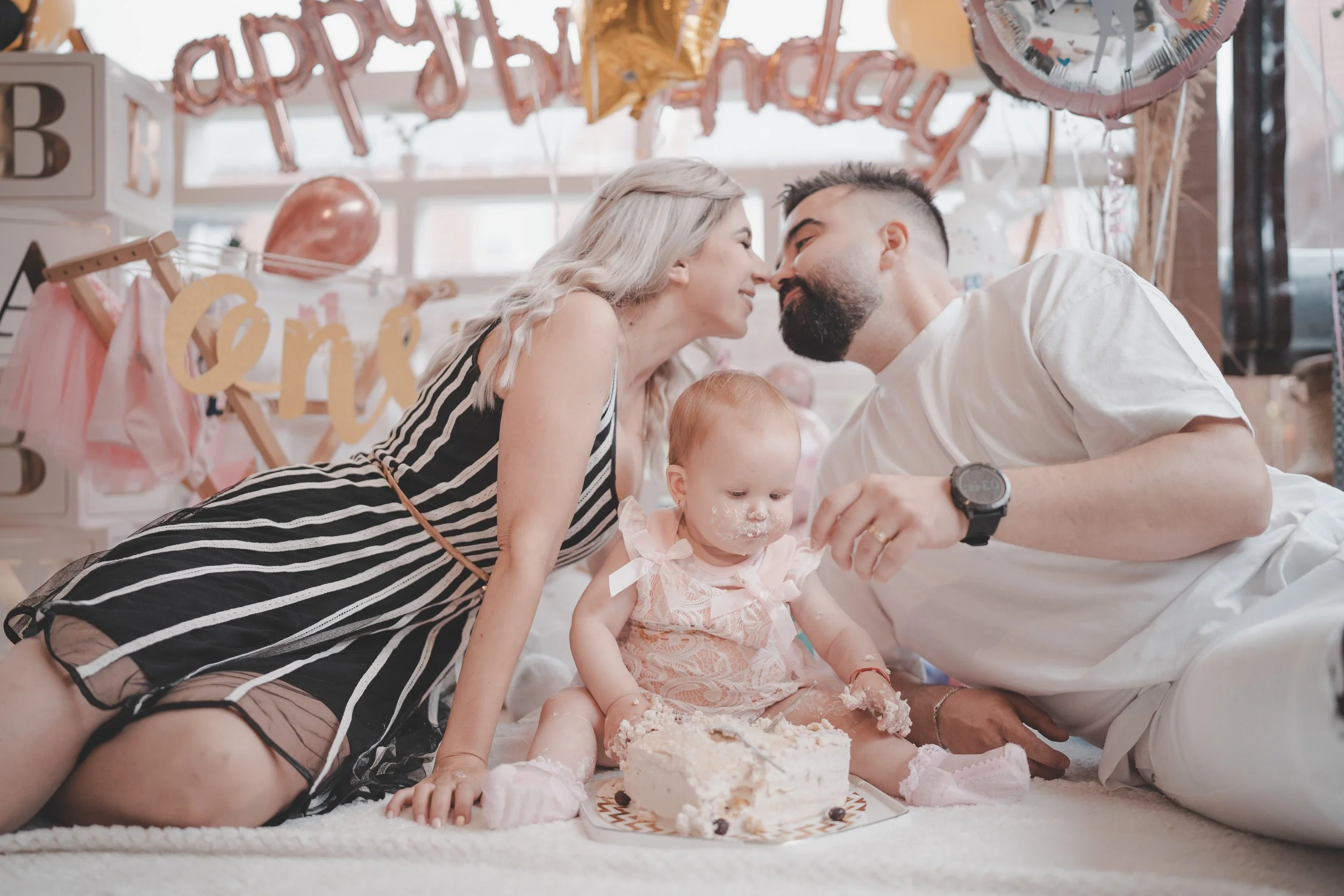 Parents kissing during their little girls smash the cake