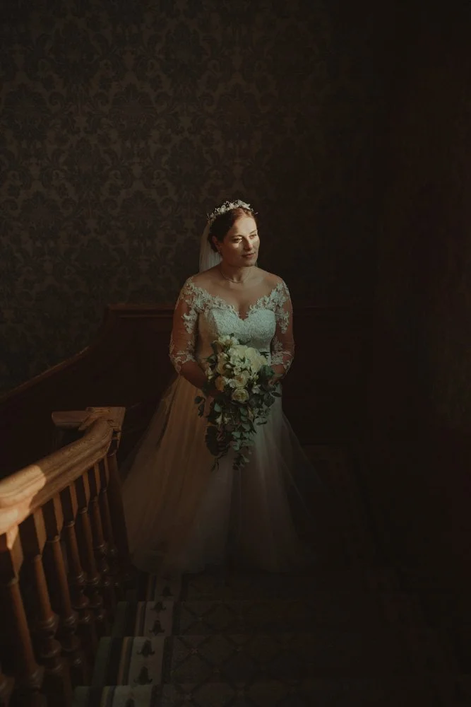 Bride photographed in the shadows, on the staircase of Brockencote Hall Hotel, Kidderminster