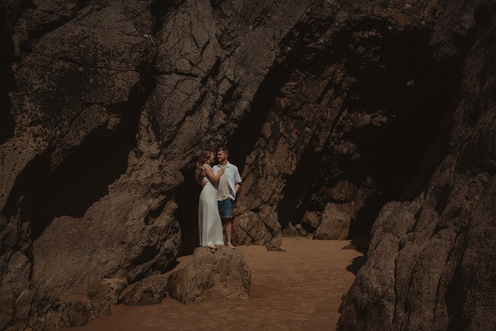 Couple wearing white in front of the cliffs of Three Cliffs Bay, Wales, UK