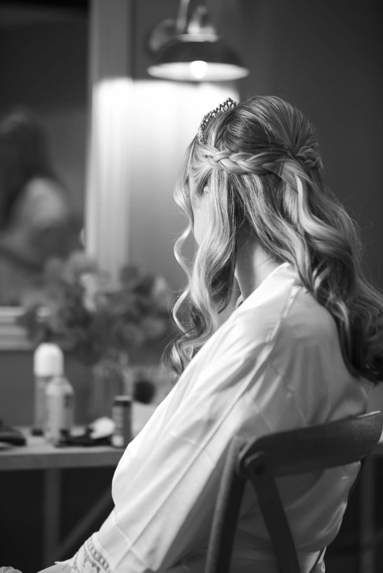 Back view of a woman with long, curly, brown hair with subtle highlights, wearing a black top.