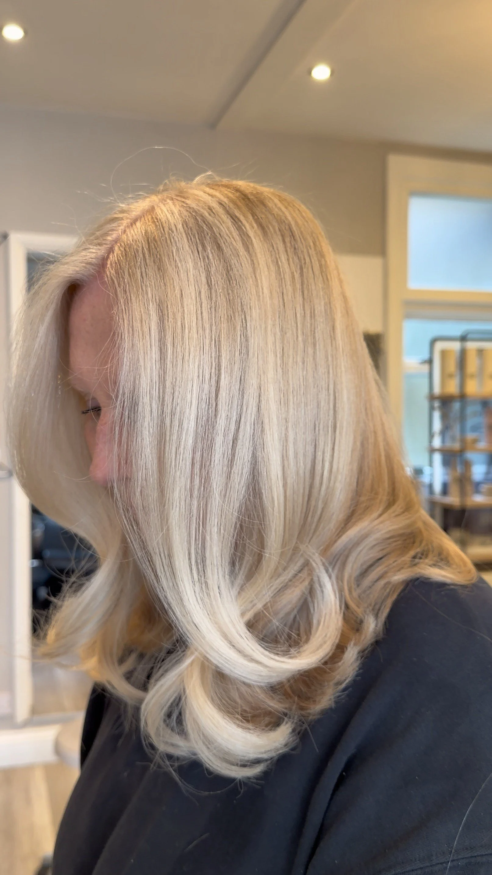 A woman with blonde, wavy hair in a salon or similar setting.