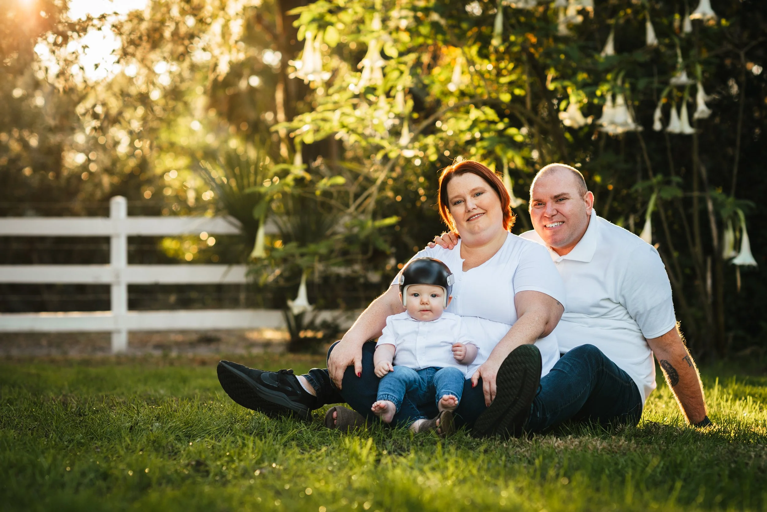 Parents sitting in grass with toddler son at sunset, Lithia Acres FL