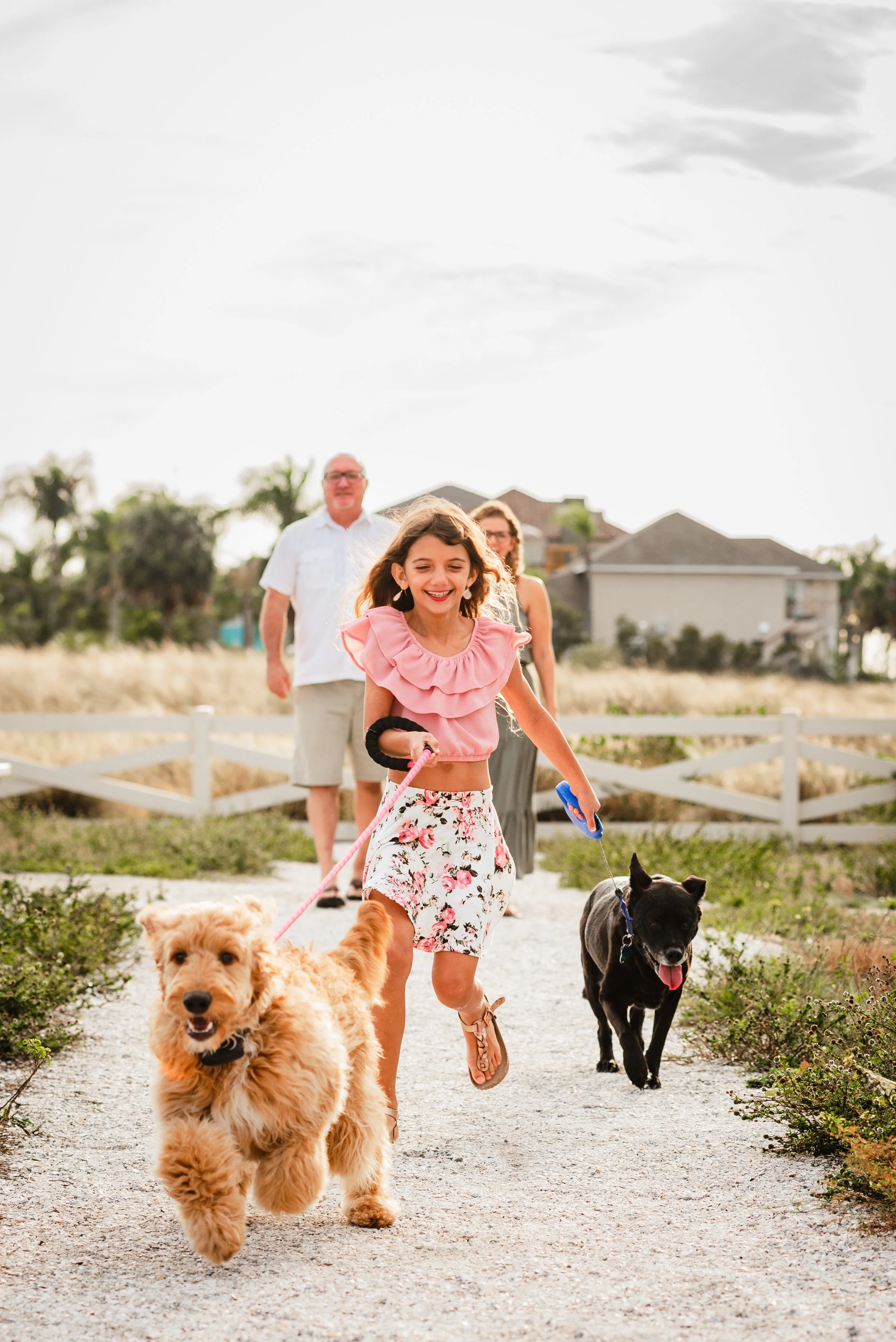 Girl running with two family dogs on leashes along a path at Apollo Beach Nature Preserve